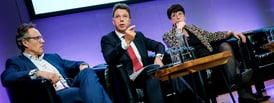 Three people speaking at a conference