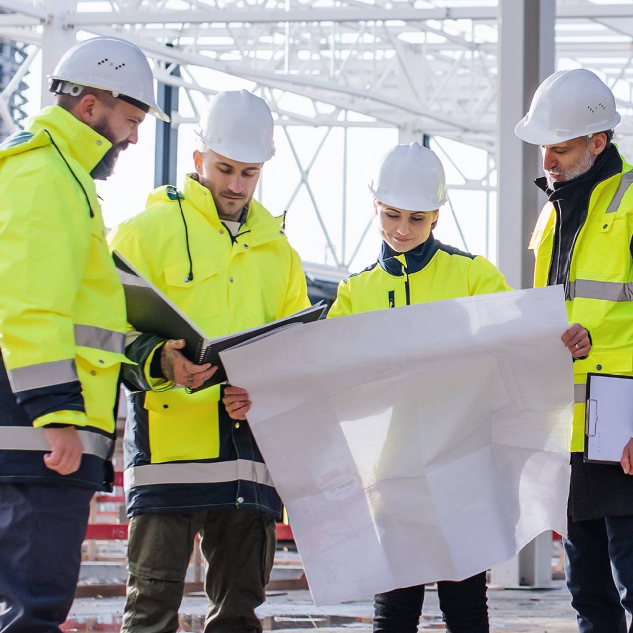 Group of engineers with blueprints standing on construction site